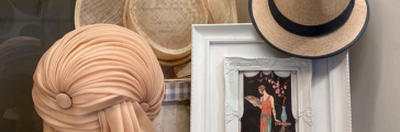Display in tweedehandswinkel Secondhand Rose met hoedjes, een paar kleurrijke pumps en een fotolijstje.
