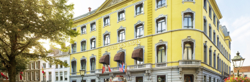 Historisch hotel met gele gevel en vlaggen