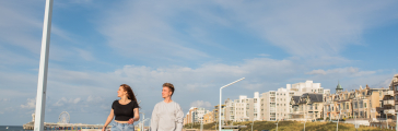 Two young people walking along the Scheveningen promenade.
