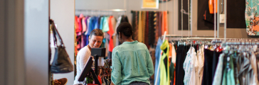 Twee vrouwen in gesprek bij de kassa van de tweedehands kledingwinkel ReShare Store Den Haag.